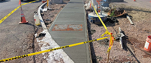 Freshly poured concrete sidewalk at the northwest corner of Flynn Avenue at the Parkway.